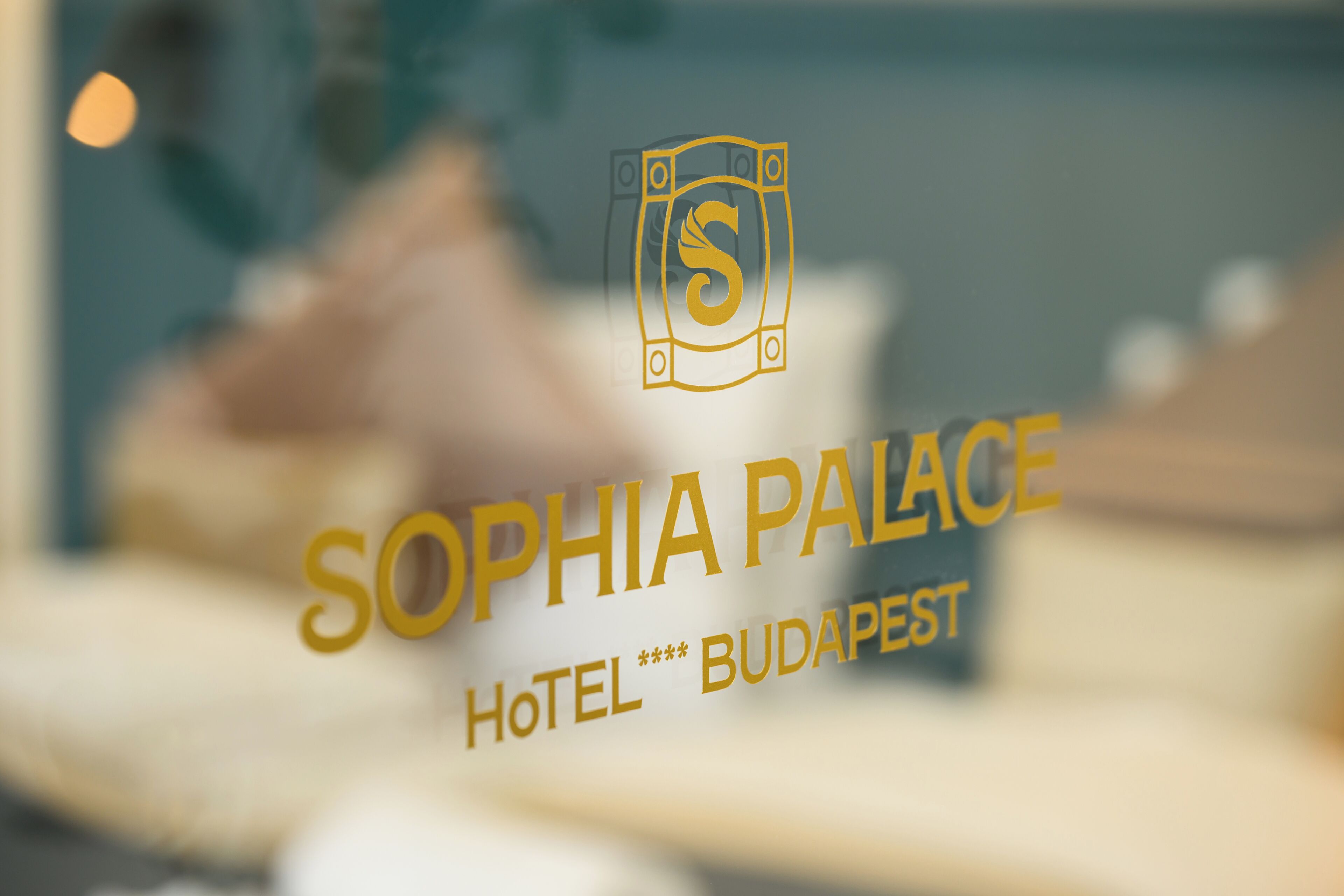 Vista borrosa del interior de un hotel, con el logotipo y el nombre 'Sophia Palace Hotel Budapest' a la vista.