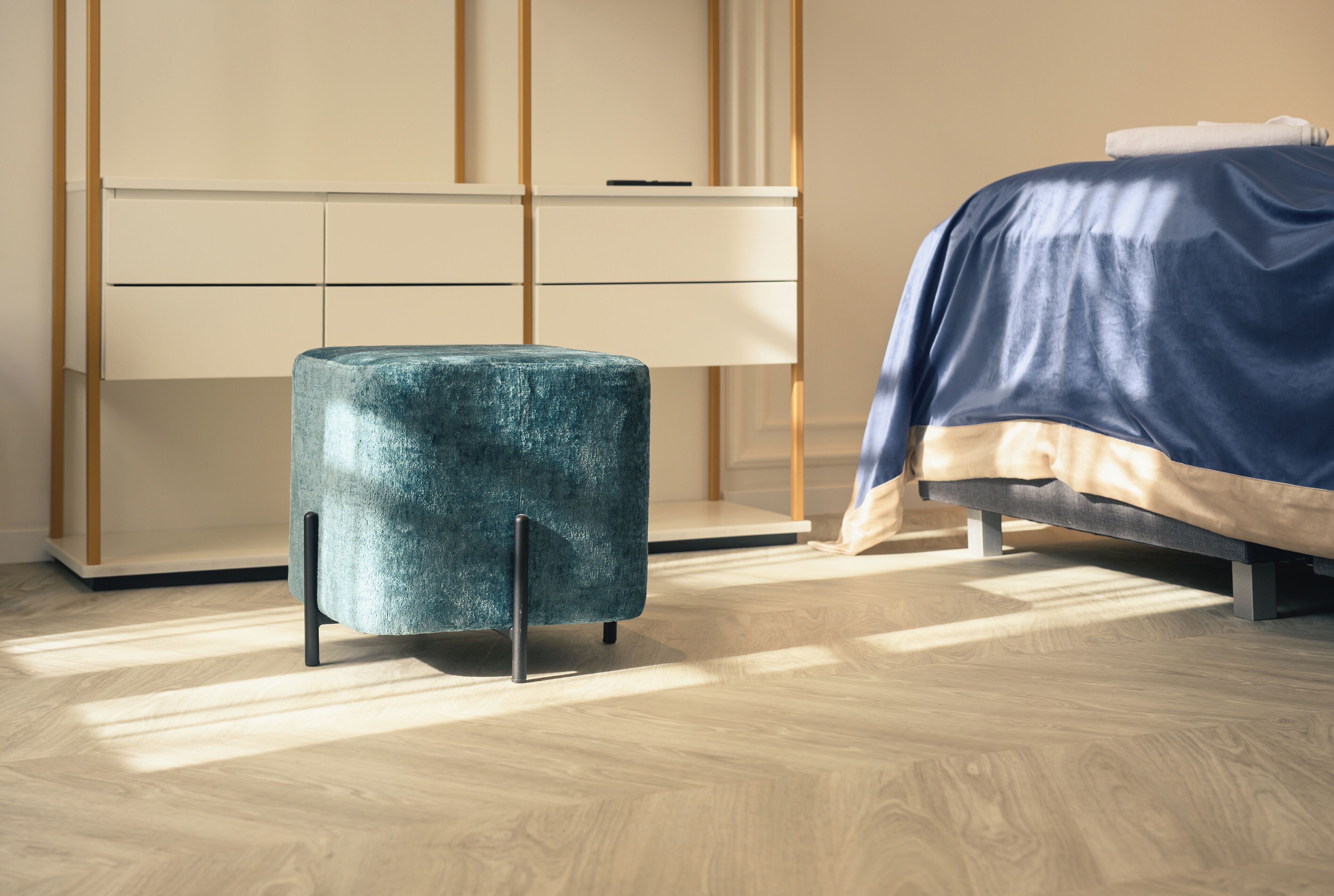 A bedroom with a bed, a bedside table, a wardrobe, and a small stool.