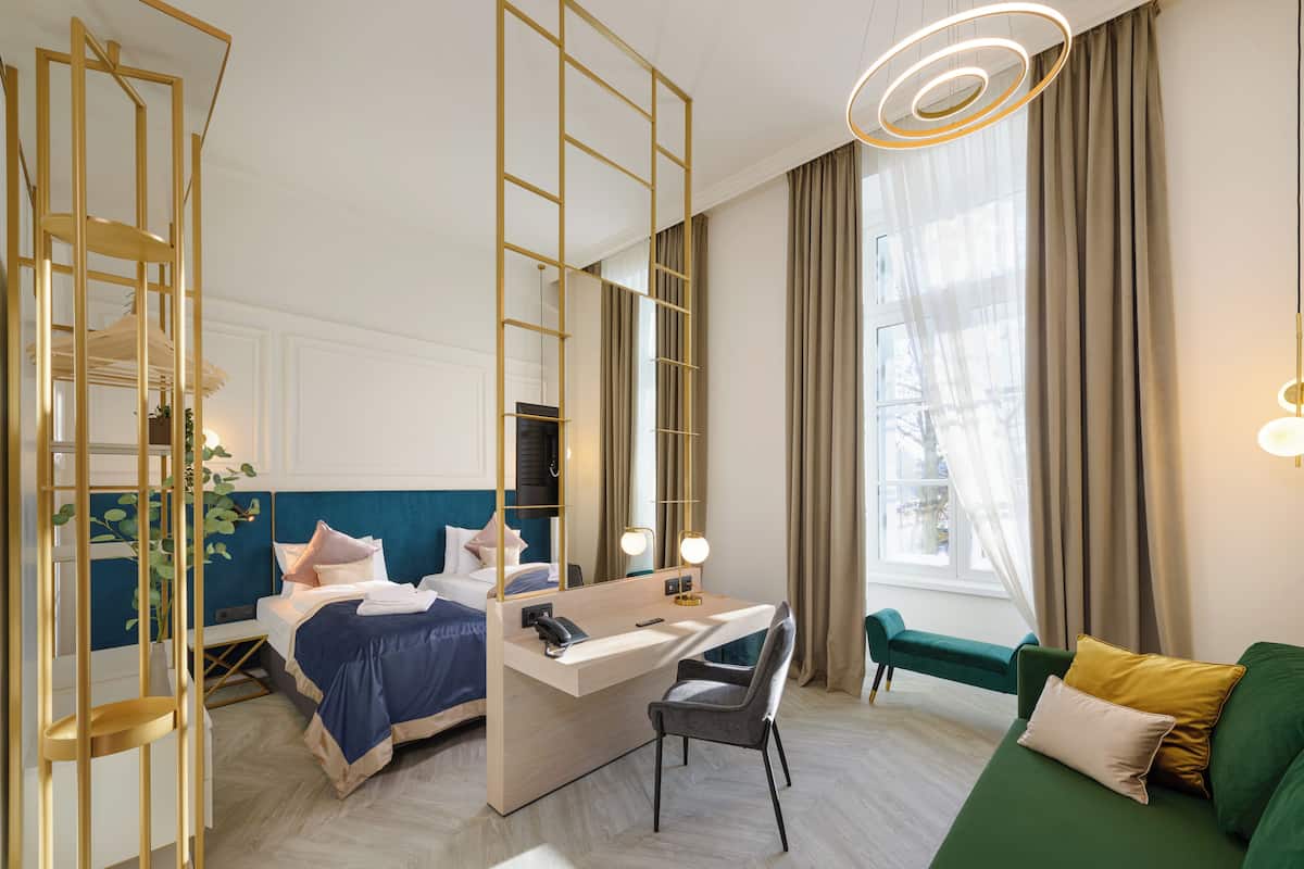 A hotel room with a bed, desk, chair, and a green sofa.