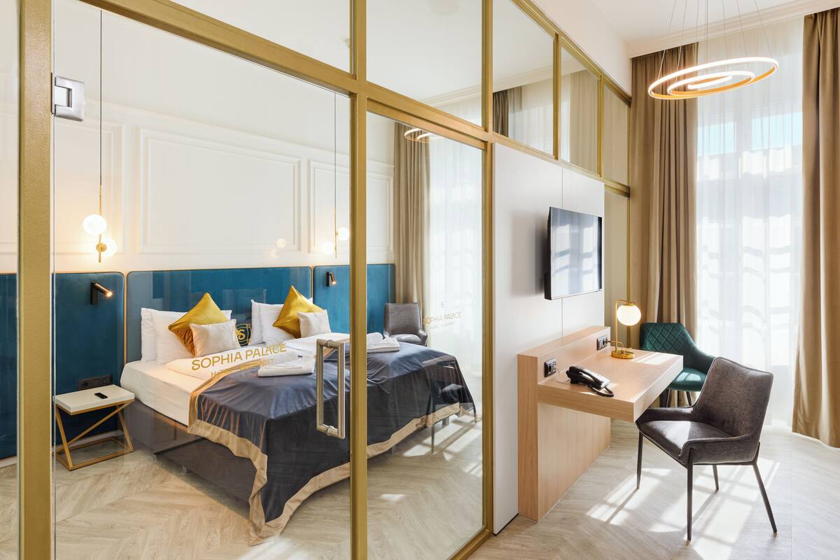 A hotel room with a bed, desk, chair, and a TV.