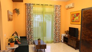 A living room with a sofa, a coffee table, a TV stand, and a potted plant. - LA VENENCIA II APARTMENT (Jerez de la Frontera)