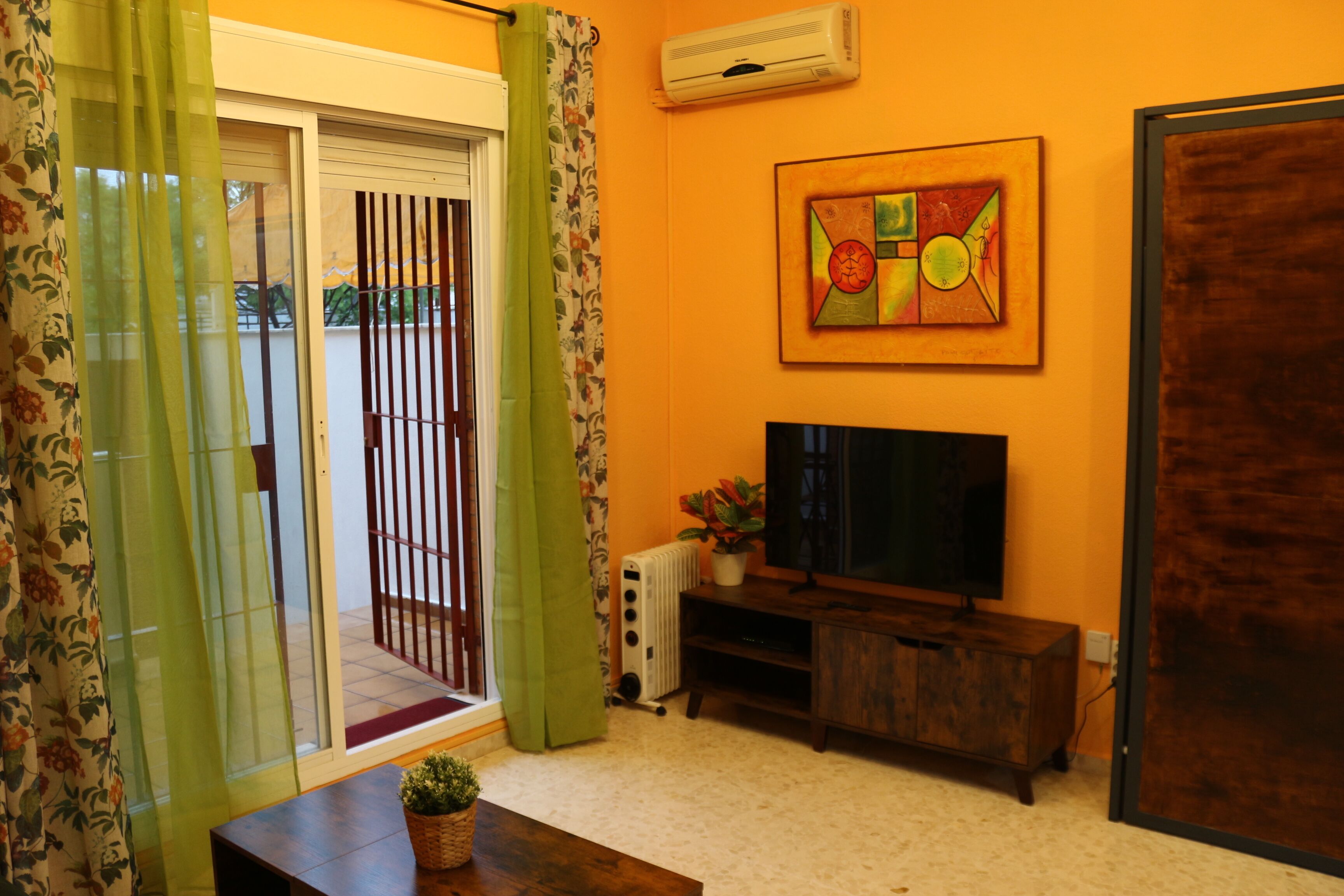 A living room with a television, a radiator, and a painting on the wall.