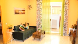 A living room with a green sofa, a small coffee table, and a white side table with a plant. - LA VENENCIA II APARTMENT (Jerez de la Frontera)