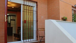 A residential building with a brick exterior, a sliding glass door, a small balcony with a plant, and a tiled floor. - LA VENENCIA II APARTMENT (Jerez de la Frontera)