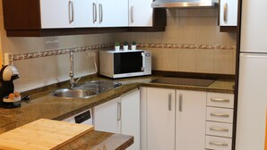 A kitchen with white cabinets, a stainless steel sink, a microwave, and a toaster. - LA VENENCIA II APARTMENT (Jerez de la Frontera)