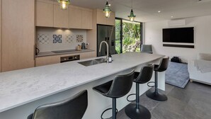 Uma cozinha moderna com uma ilha grande, banquetas e iluminação pendente.