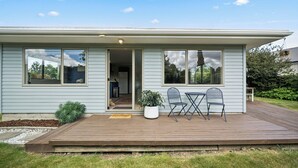Ein zweistöckiges Haus mit einer Terrasse, zwei Stühlen, einem Tisch und einem Blumentopf.