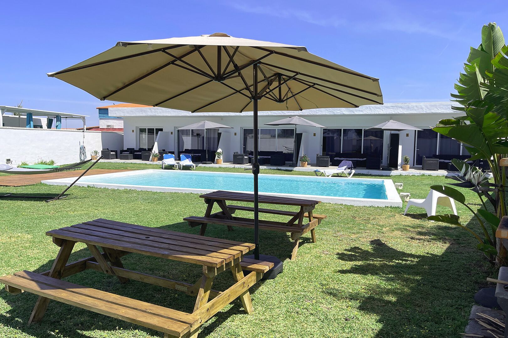 A backyard with a swimming pool, a wooden picnic table, and lounge chairs.