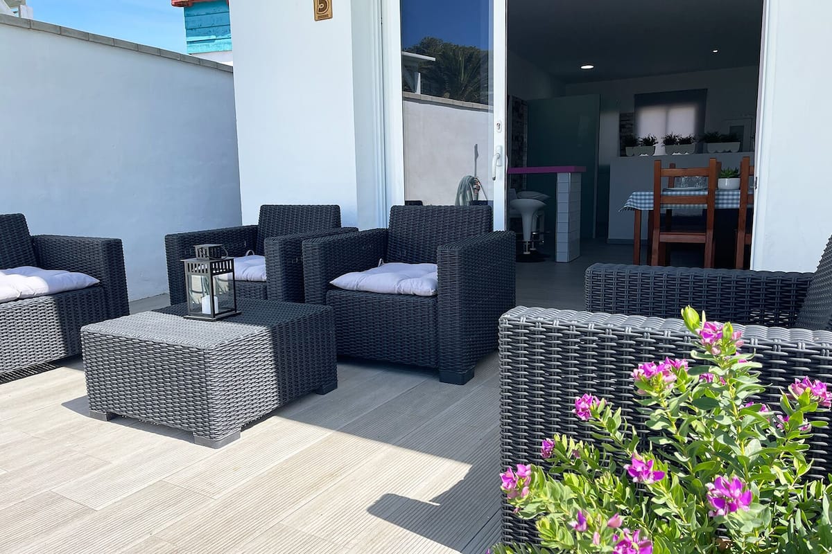 An outdoor seating area with wicker furniture and a potted plant.