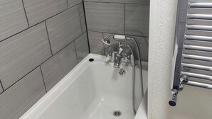 A bathroom with a bathtub, a shower, and a towel rack. - Couples/business/family- Wifi- Parking- Sleeps 2 (Coventry)