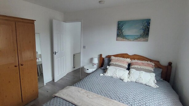 A bedroom with a bed, a wooden wardrobe, a white door, and a painting on the wall. - Couples/business/family- Wifi- Parking- Sleeps 2 (Coventry)
