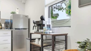 Een moderne keuken met een roestvrijstalen koelkast, een koffieapparaat en een raam met uitzicht op groen.