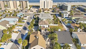 Een kustwoongebied met een mix van eengezinswoningen en appartementencomplexen, met uitzicht op het strand en met palmbomen.