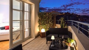 A balcony with a sofa, a table with a lamp, and a potted plant. - LEOPOLDO ROOMS (Cagliari)