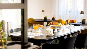 A breakfast setting with a table set for two, featuring a variety of pastries, a teapot, and a glass of orange juice. - LEOPOLDO ROOMS (Cagliari)