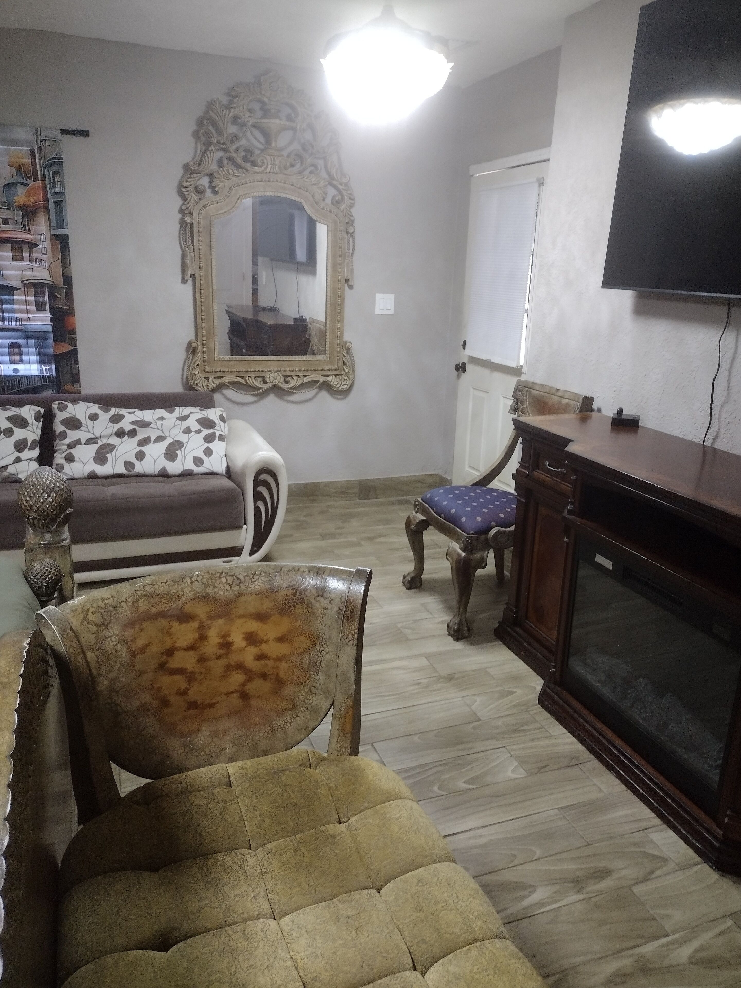 Una sala de estar con un sofá, una silla, un televisor y una chimenea.