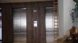 Un ascensor moderno con paneles de madera, un panel de control y una puerta metálica.