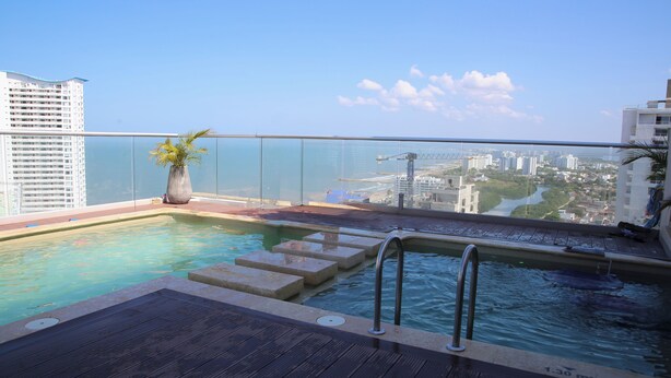 Una piscina en la azotea con vistas despejadas del paisaje urbano y una palmera.