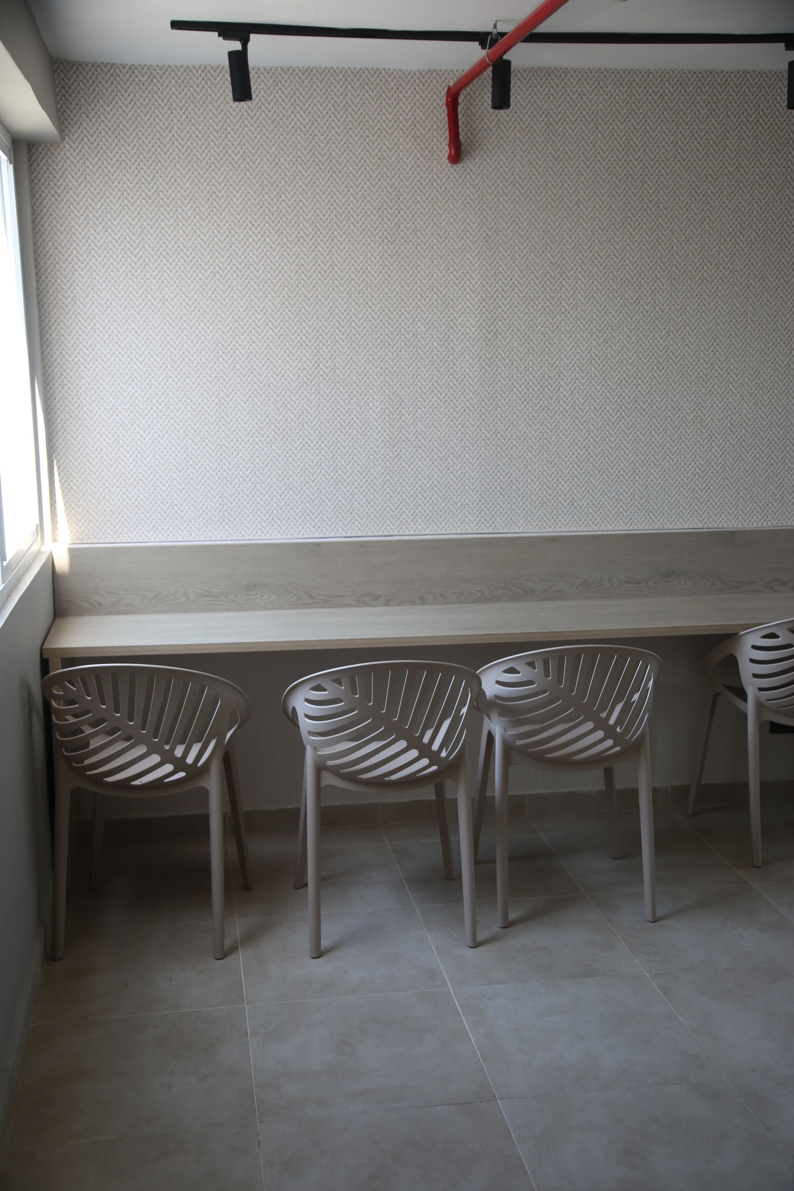 A seating area with a bench and three chairs against a wall with a herringbone pattern.