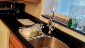 A kitchen with wooden cabinets, a stainless steel sink, a coffee maker, and a window above the sink. - Pleasant 1-bedroom house with AC in sunny Orlando (Orlando)