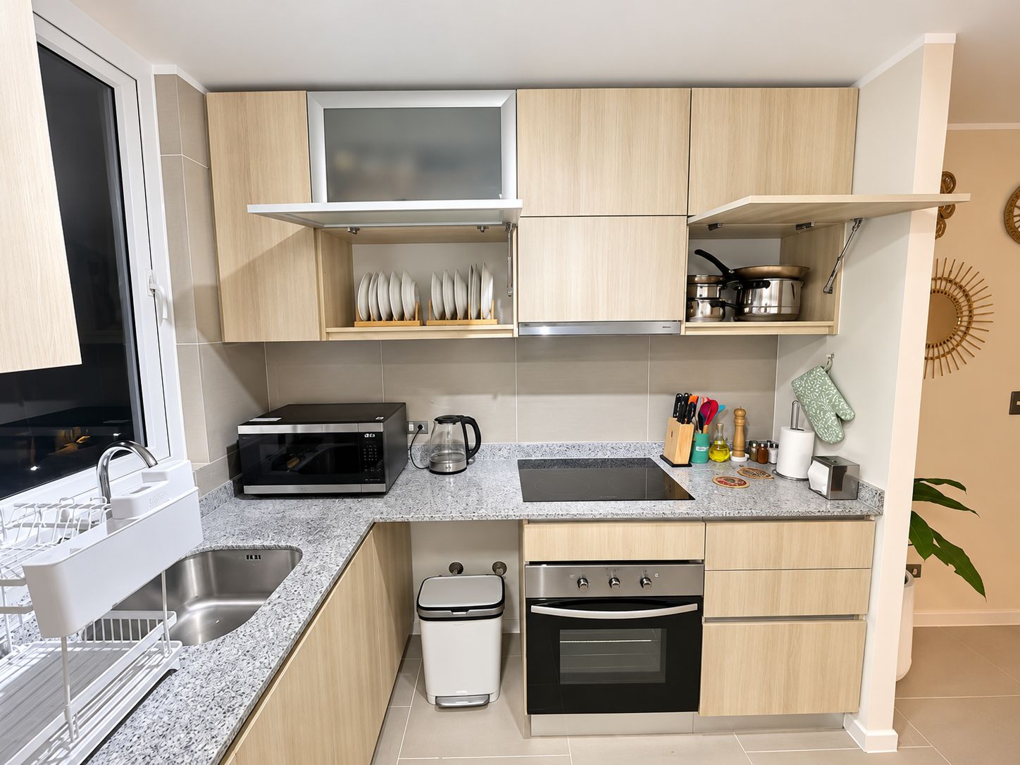 A compact kitchen with a built-in oven, a microwave, a sink, and a coffee maker.