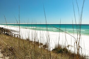 A beach with white sand and tall grasses in the foreground. - Walk to the beach, Seagrove, Cassine Gardens, Pools, Trails, & More! (Santa Rosa Beach)
