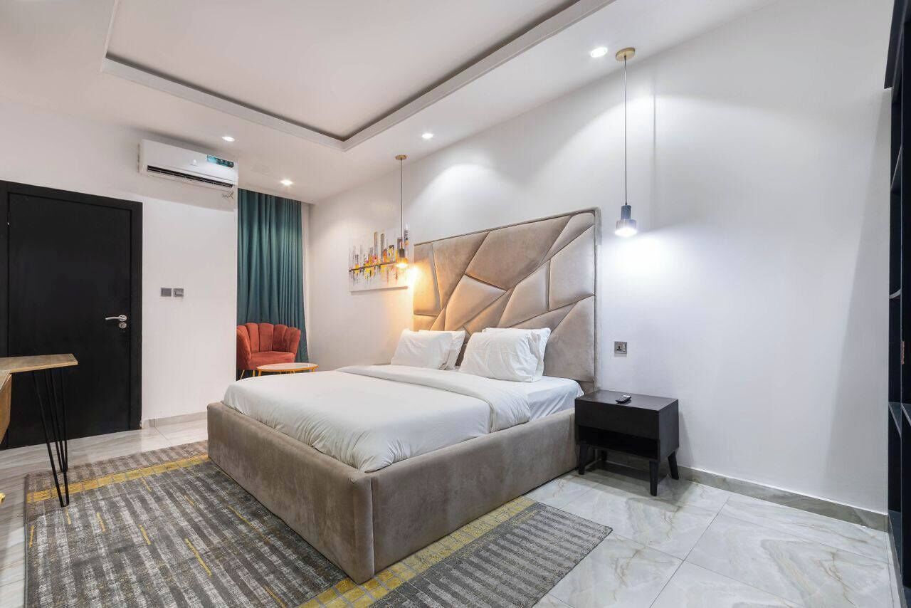 Una camera da letto moderna con un letto grande, un comodino, una sedia e un lampadario a parete.