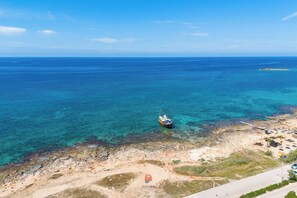 An aerial view of a coastal area with clear blue waters, a boat, and a sandy beach with some structures. - Pergolaris holiday By Vivimy (Ugento)