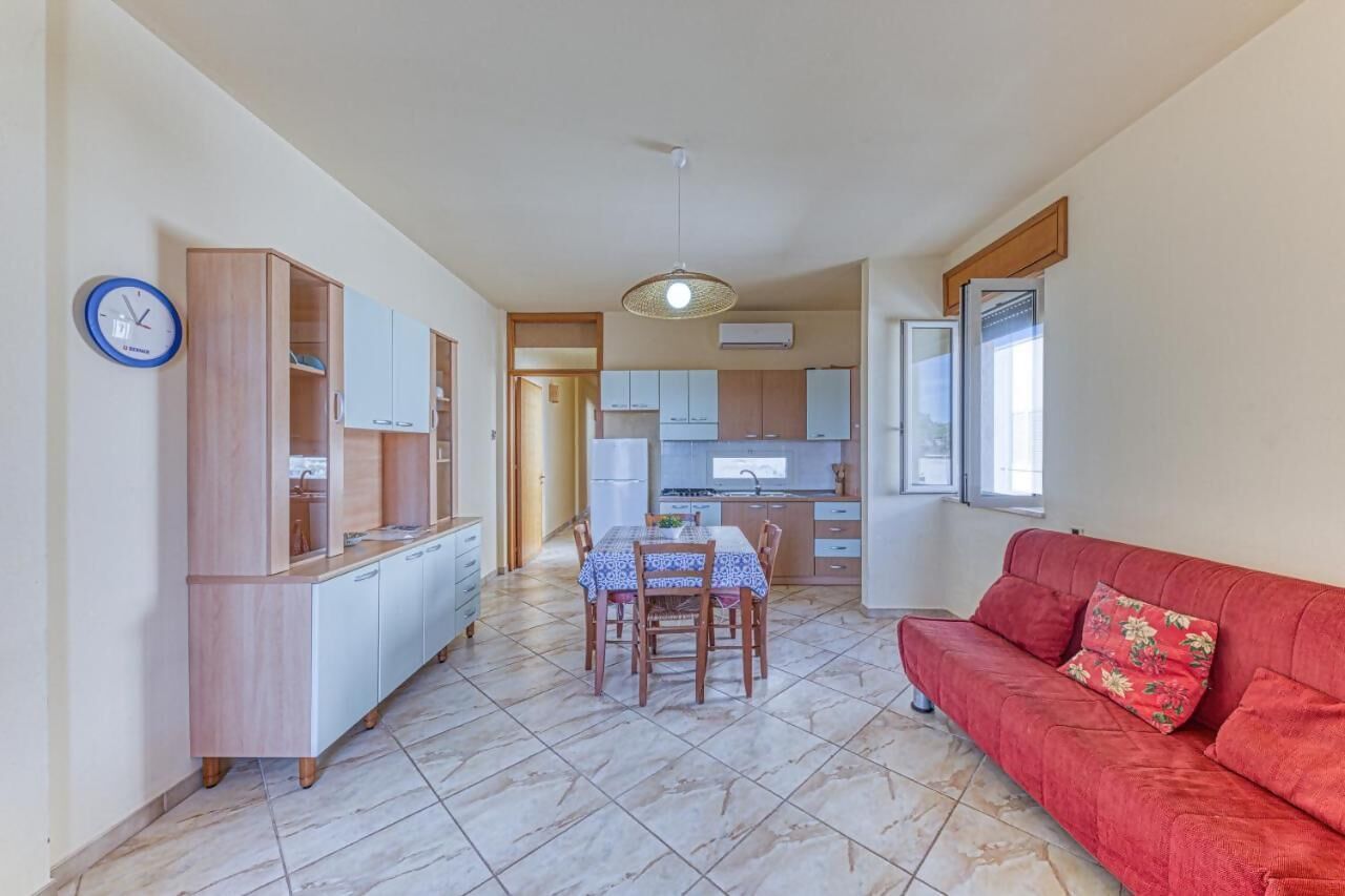 A compact living space with a dining area, kitchenette, and a red sofa.