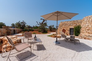 Un área de estar al aire libre con paredes de piedra, una mesa y sillas.