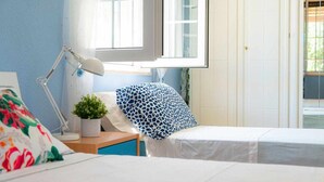 Een slaapkamer met twee bedden, een bureau, een lamp en een raam.