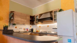 Een keuken met houten kastjes, een zwart aanrecht, een witte koelkast en een inbouwfornuis.