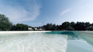 A clear swimming pool with a view of a building and trees in the background. - Villa Sole By Vivimy (Parabita)