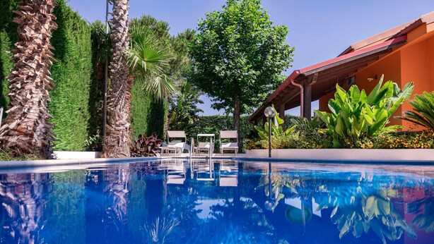 Une piscine d’un bleu éclatant, dotée de chaises longues, et un bâtiment aux murs orange.