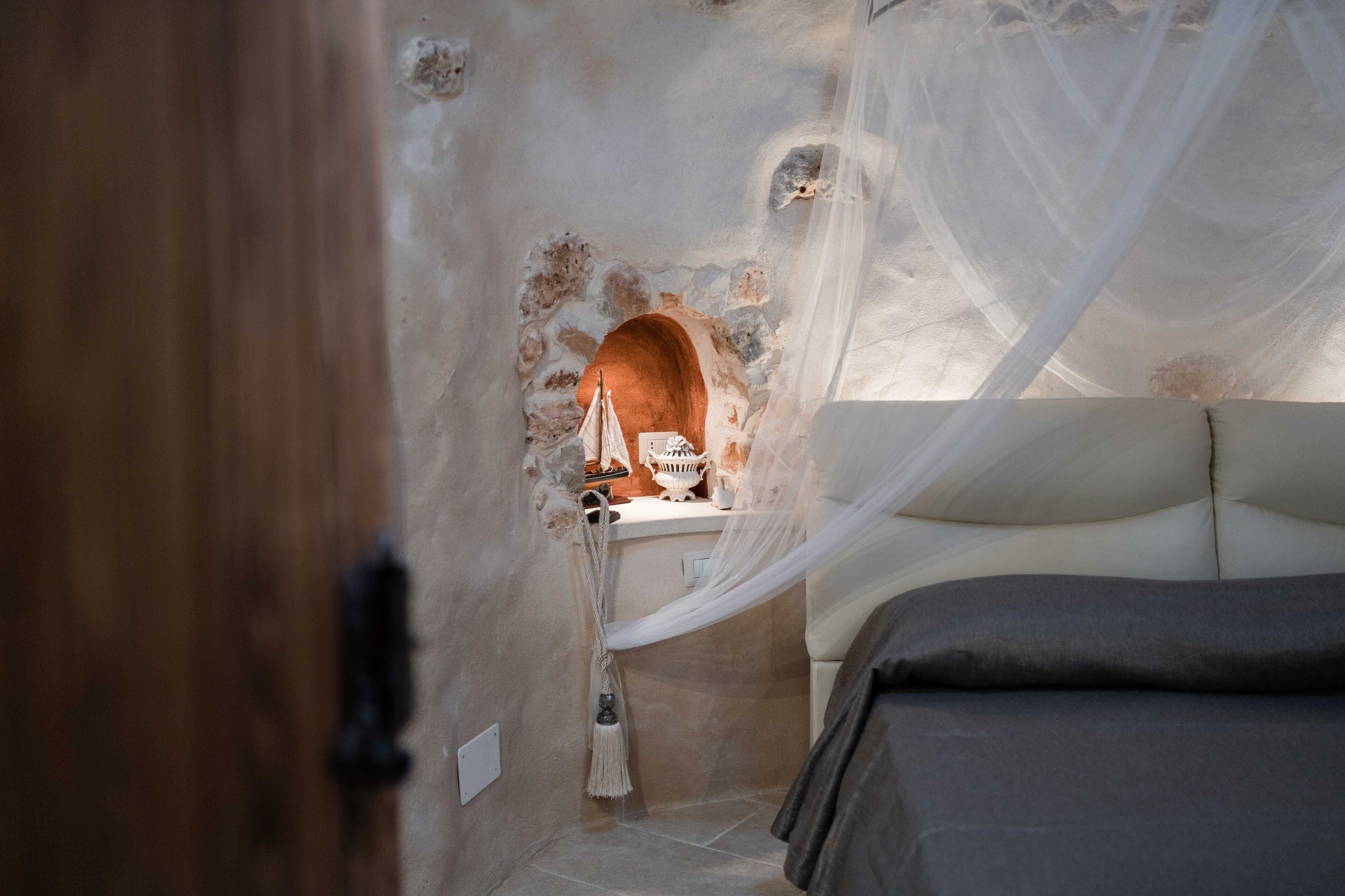 Una camera da letto con un letto, un tavolino con una lampada e un arco decorativo.