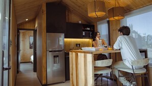 Una cocina moderna con armarios de madera, un refrigerador de acero inoxidable y una zona de comedor con una trona y una mesa.
