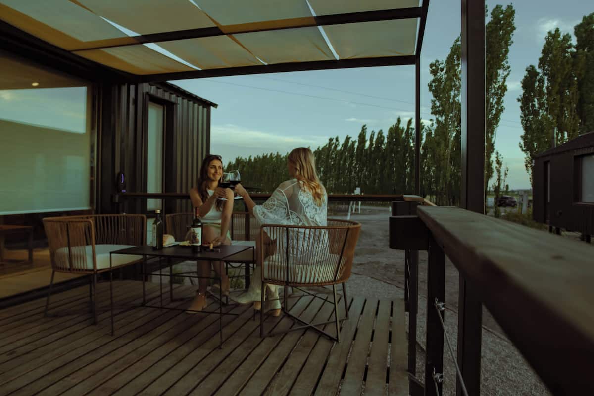 An outdoor patio with wooden flooring, metal chairs, and a table.