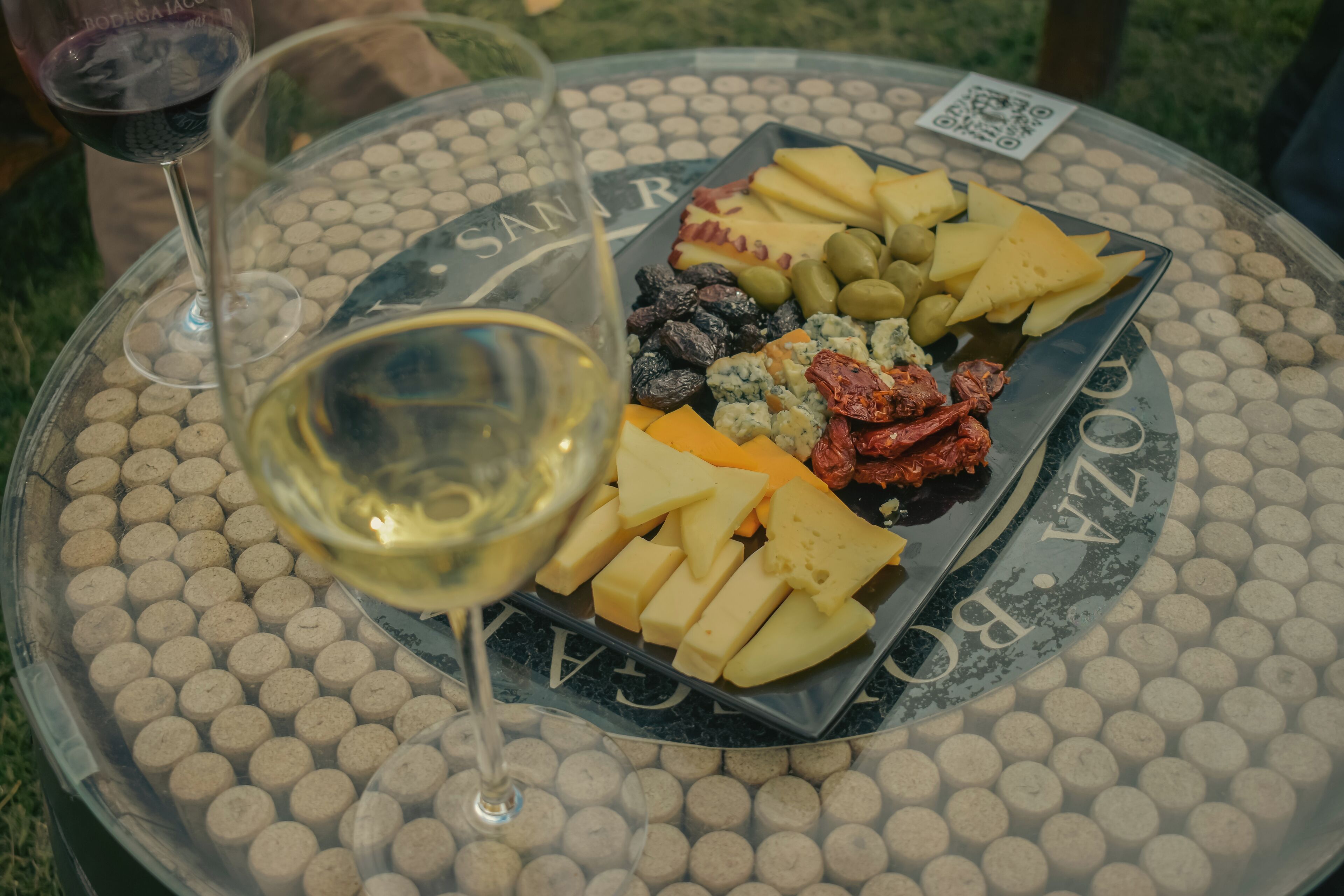 A round table with a glass wine glass and a charcuterie board.