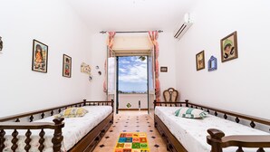 Ein Zimmer mit zwei Holzbetten, einer bunten Spielmatte und einem Fenster mit Blick.