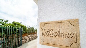 Ein Schild mit der Aufschrift "Villa Anna" an einer weißen Wand.