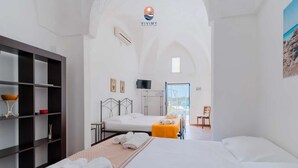 Habitación de hotel con cama, televisión, escritorio y vista a la playa.