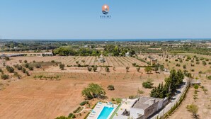 Vista aérea de una propiedad con piscina, rodeada de campos y árboles dispersos.