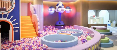 Un espace de jeux pour enfants avec une piscine à balles, des toboggans et une structure d’escalade.