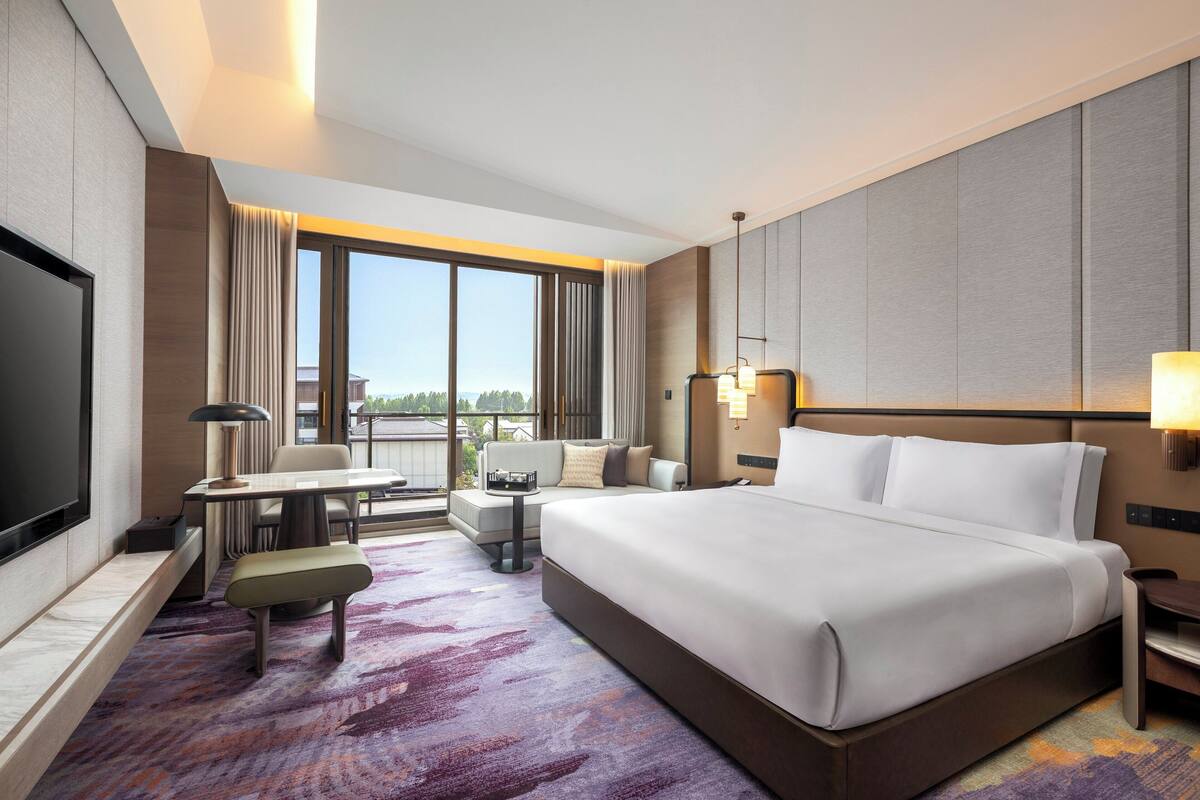 Une chambre d’hôtel avec un grand lit, un bureau, une chaise, un canapé et une télévision.