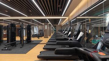 Un gimnasio con cintas de correr, máquinas de pesas y espejos en las paredes.