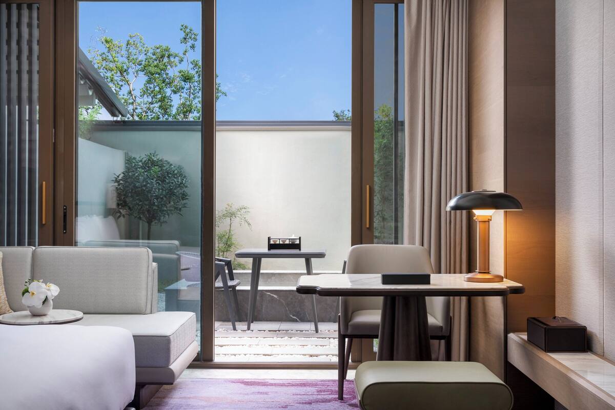 Een moderne hotelkamer met een bank, een tafeltje, een lamp en uitzicht op het landschap.