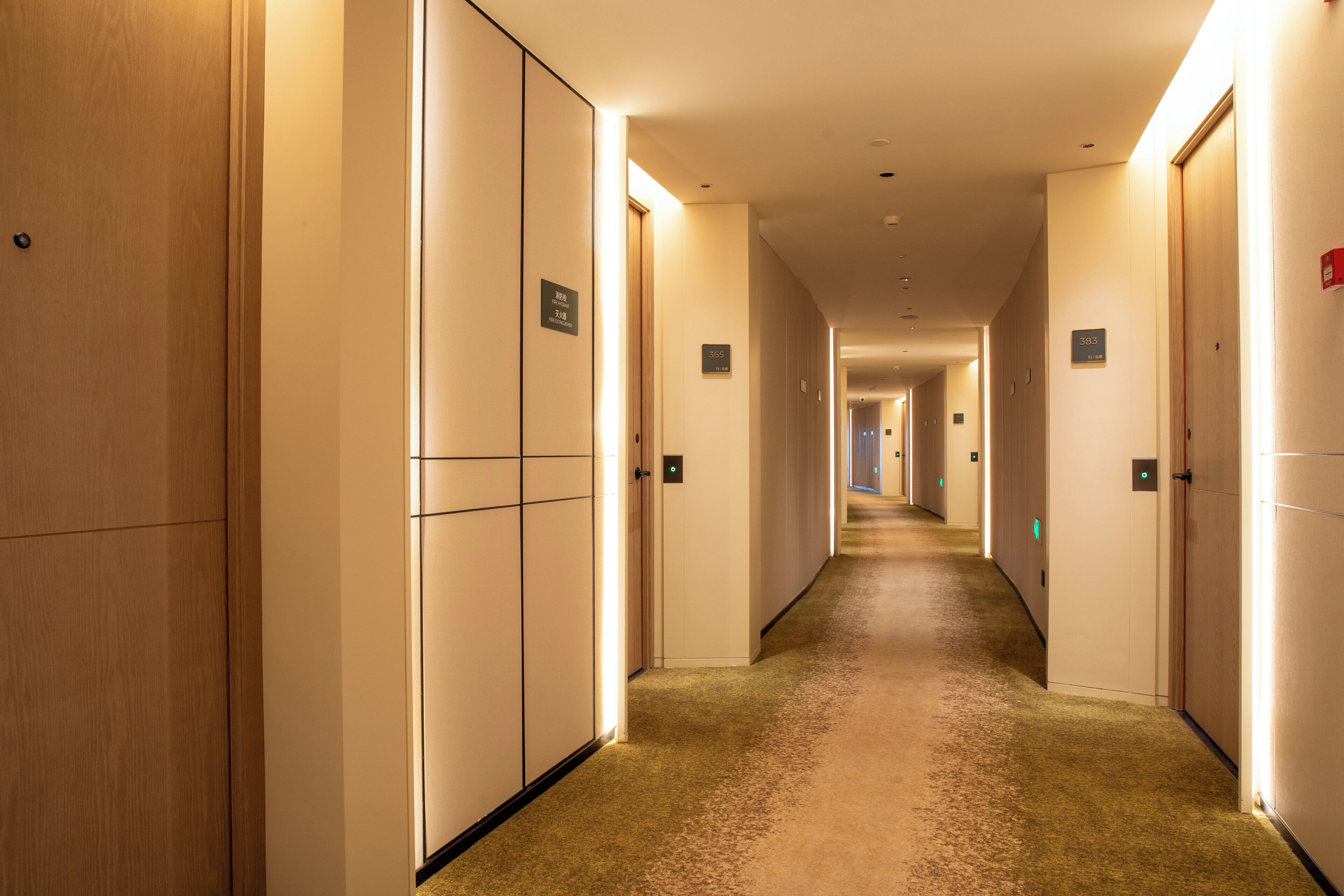 A hotel corridor with multiple doors, each marked with a number.
