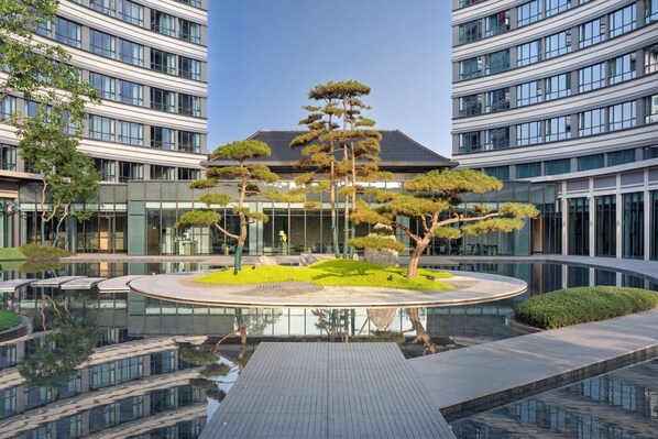 Un edificio moderno con una fuente circular central rodeada de árboles.