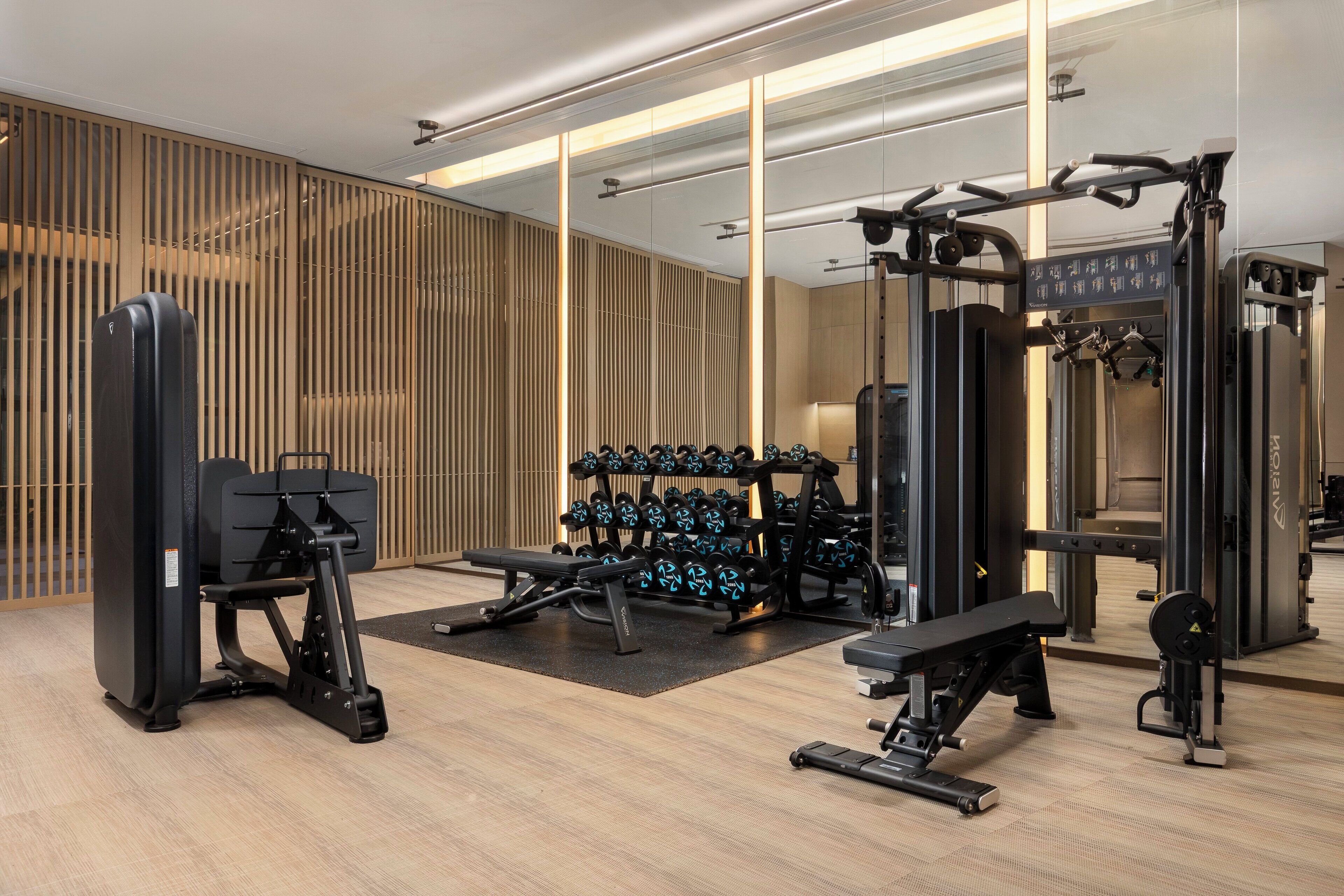 Un gimnasio moderno con diversos equipos de ejercicio, como una prensa de banca, mancuernas y máquinas de pesas.