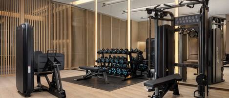 Un gimnasio moderno con diversos equipos de ejercicio, como una prensa de banca, mancuernas y máquinas de pesas.